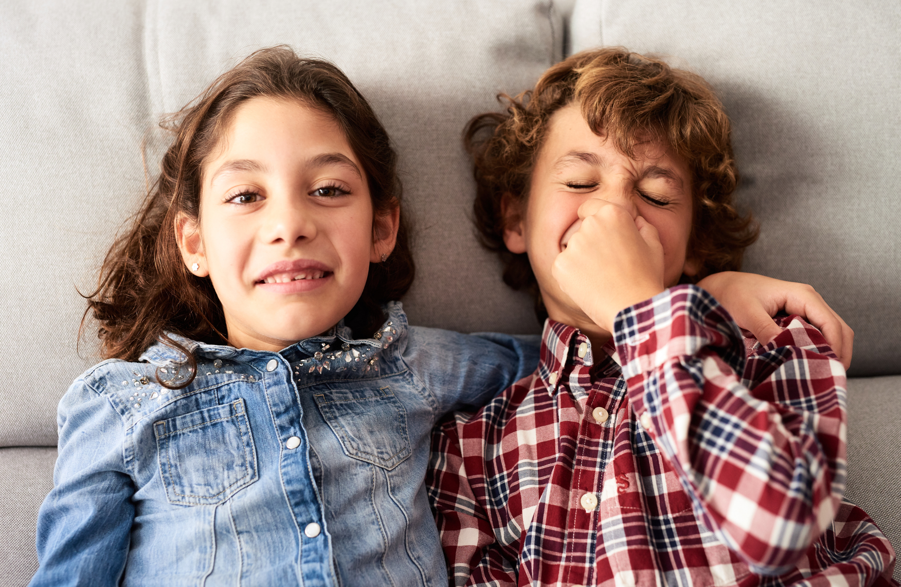 Kids laughing on a couch.